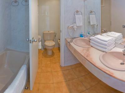 Łazienka hotelowa z wanną, toaletą i dużą umywalką z ręcznikami.