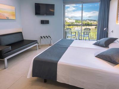 Nowoczesny pokój hotelowy z łóżkiem podwójnym, sofą, telewizorem na ścianie i balkonem z widokiem.