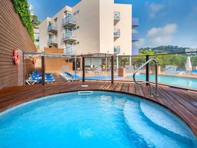 Nowoczesne jacuzzi z widokiem na basen i budynek hotelu pod słonecznym niebem.