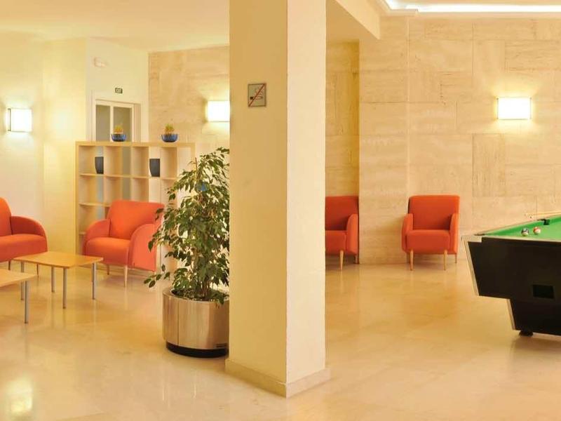 Jasna przestrzeń wypoczynkowa z czerwonymi fotelami i stołem do bilarda w hotelu.