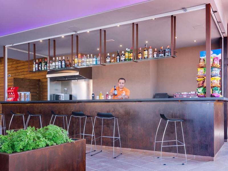 Nowoczesny bar hotelowy z hokerami, wyborem napojów i rustykalną atmosferą.