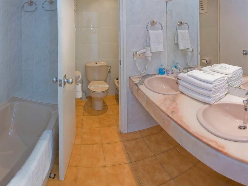 Łazienka hotelowa z wanną, toaletą i dużą umywalką z ręcznikami.