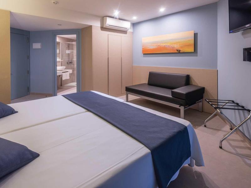 Nowoczesny pokój hotelowy z dwoma łóżkami, kanapą, klimatyzacją i obrazem na ścianie.