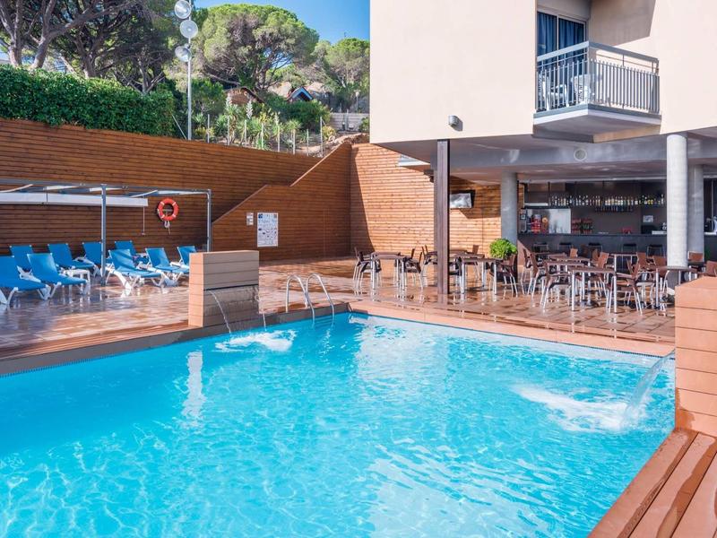 Przejrzysty basen na nowoczesnym hotelowym tarasie z stołami i krzesłami na zewnątrz.