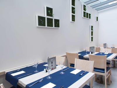 Salle à manger moderne avec nappes bleues, chaises en bois et décoration murale minimaliste.