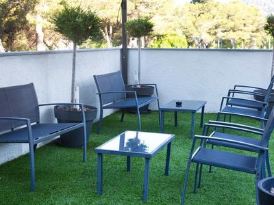 Espace extérieur moderne avec chaises bleues et tables sur gazon synthétique vert.