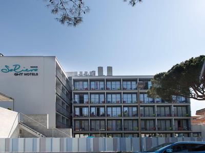 Bâtiment d'hôtel moderne avec plusieurs étages et grandes fenêtres sous un ciel clair.