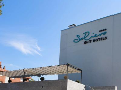 Bâtiment d'hôtel moderne avec enseigne bleue sur la façade sous un ciel ensoleillé.