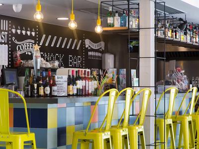 Bar moderne avec des chaises jaunes et une variété de bouteilles derrière le comptoir.