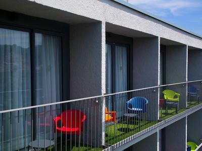 Balcon avec des chaises colorées devant une chambre d'hôtel par une journée ensoleillée.