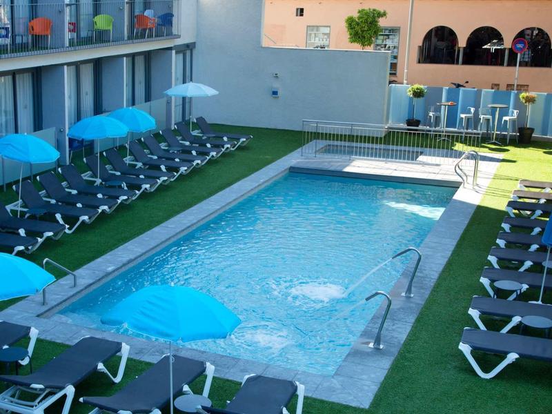 Espace piscine moderne avec chaises longues et parasols bleus sur une terrasse sur le toit.