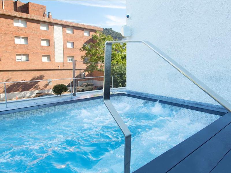 Jacuzzi avec eau bouillonnante sur une terrasse à côté d'un bâtiment blanc.