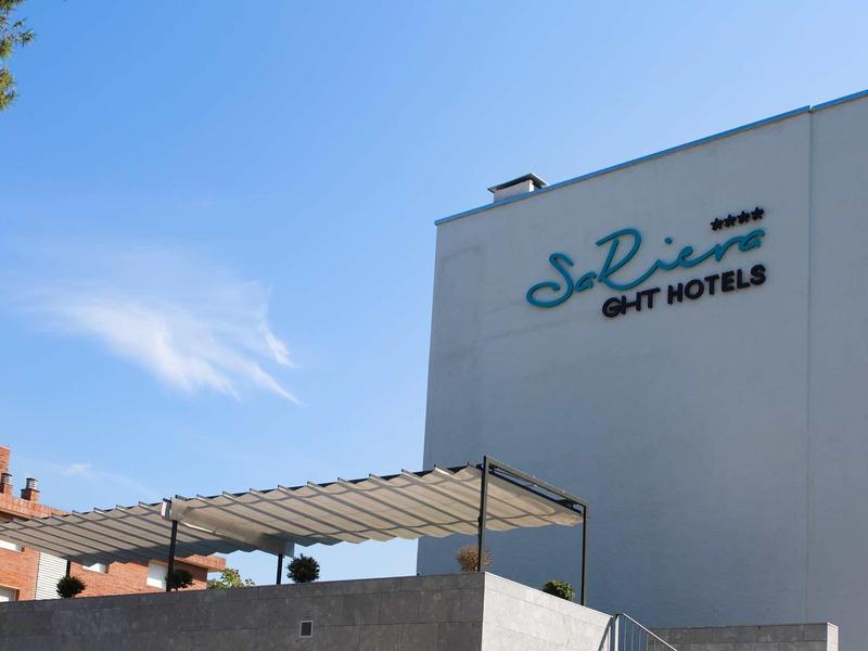 Bâtiment d'hôtel moderne avec enseigne bleue sur la façade sous un ciel ensoleillé.