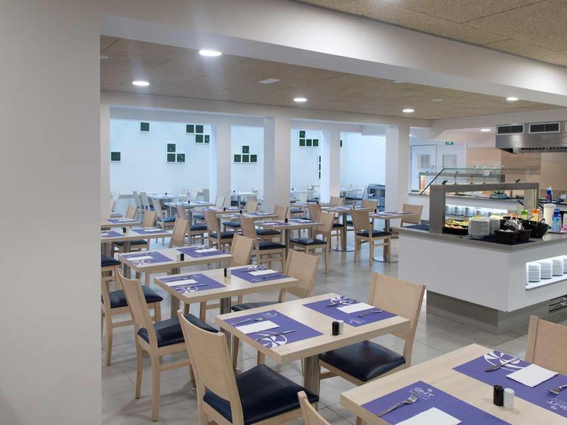 Restaurant lumineux et moderne avec murs blancs et tables dressées.