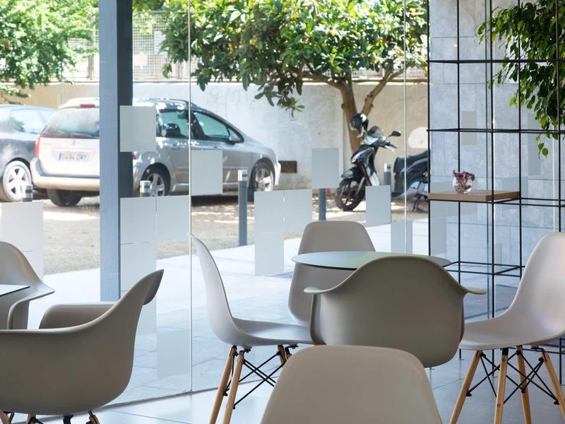 Intérieur moderne d'un café avec des chaises blanches et vue sur le parking à travers de grandes fenêtres.