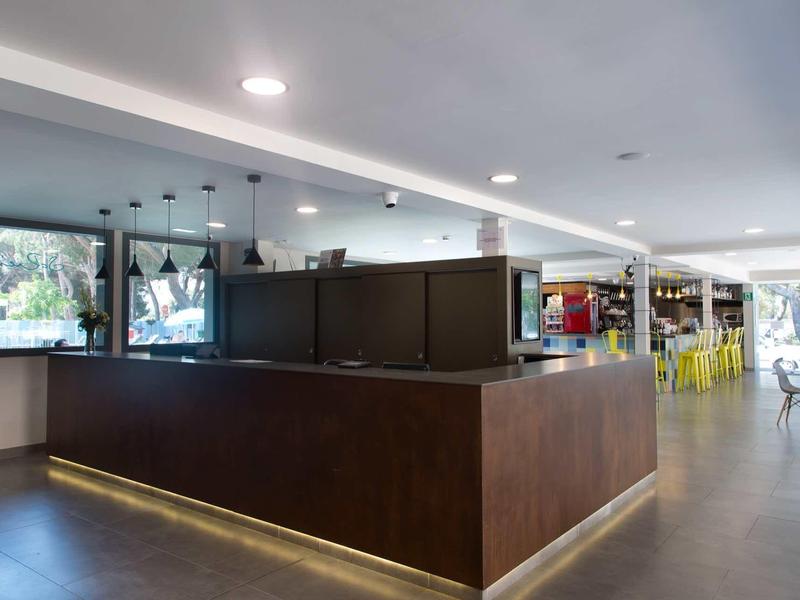 Réception d'hôtel moderne avec comptoir sombre et grandes fenêtres.