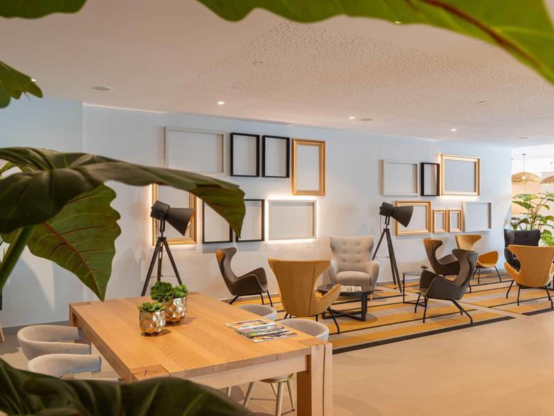 Area lounge moderna dell'hotel con tavoli in legno, sedie e decorazioni murali eleganti.