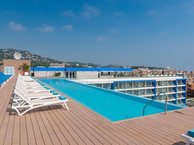 Piscina moderna sul tetto con lettini e vista sulle montagne.