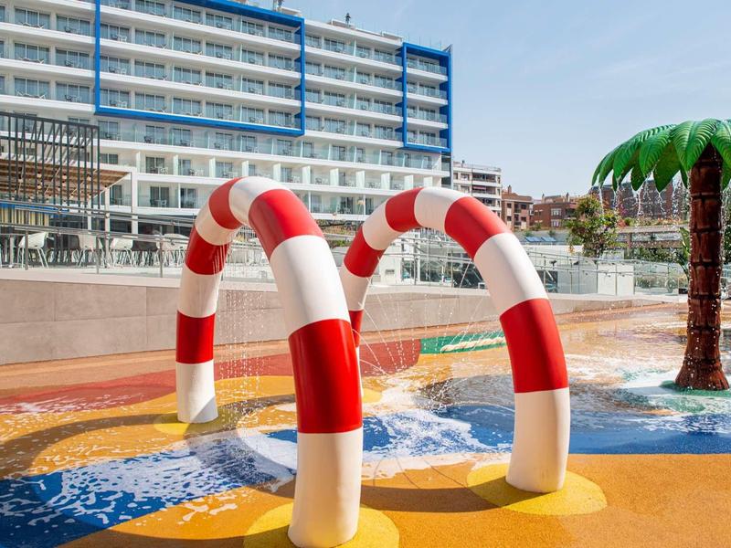 Parco acquatico per bambini con getti d'acqua rossi e bianchi e una palma.
