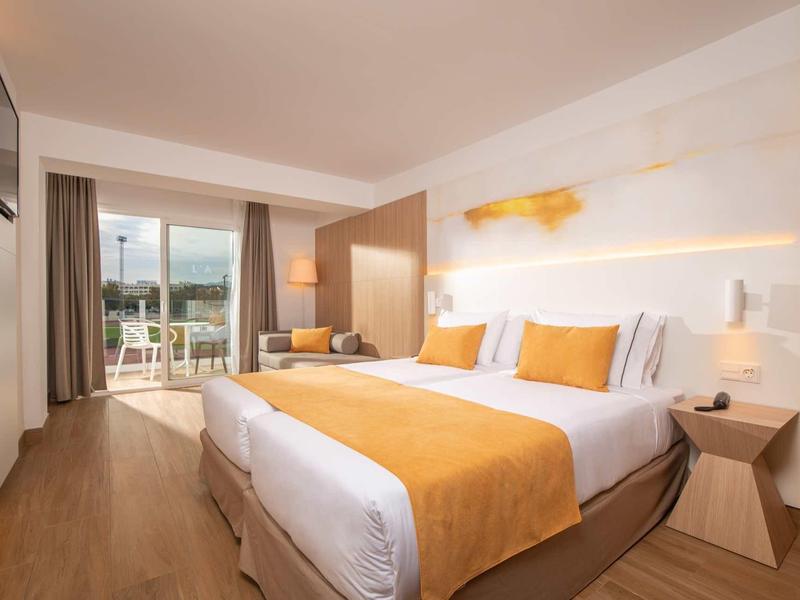 Camera d'hotel moderna con letto grande, balcone e vista sulla natura.