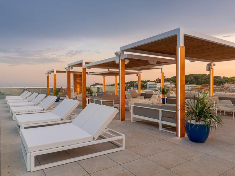Lettini moderni e aree coperte su una terrazza dell'hotel al tramonto.