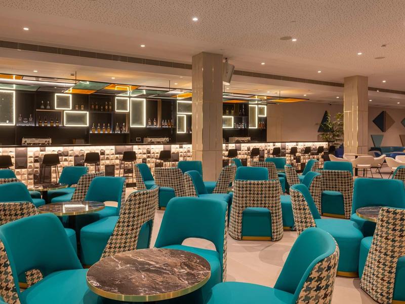 Ristorante d'hotel moderno con poltrone turchesi e tavoli in marmo.