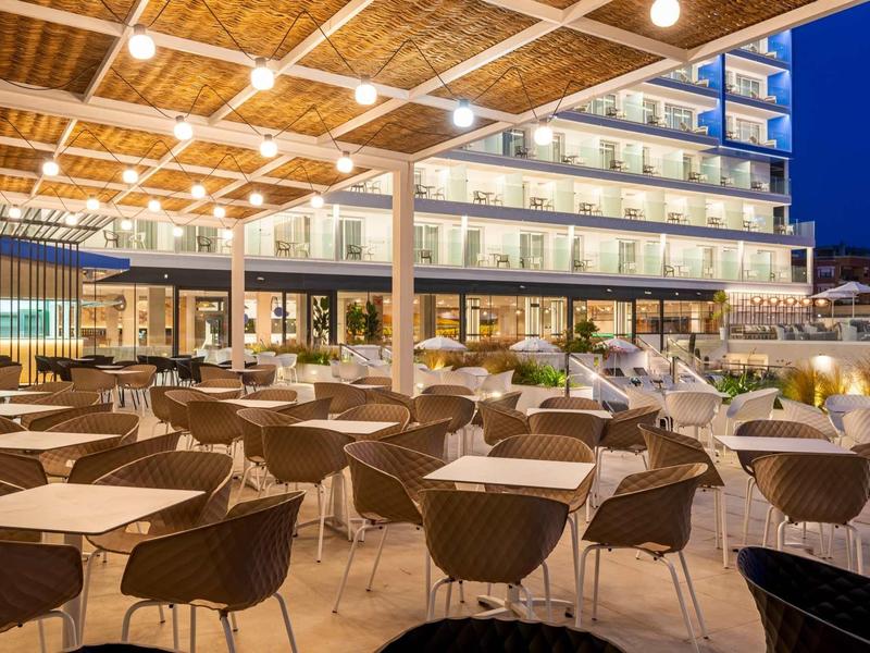 Ristorante esterno moderno e vuoto di un hotel con illuminazione e tetto in legno di notte.