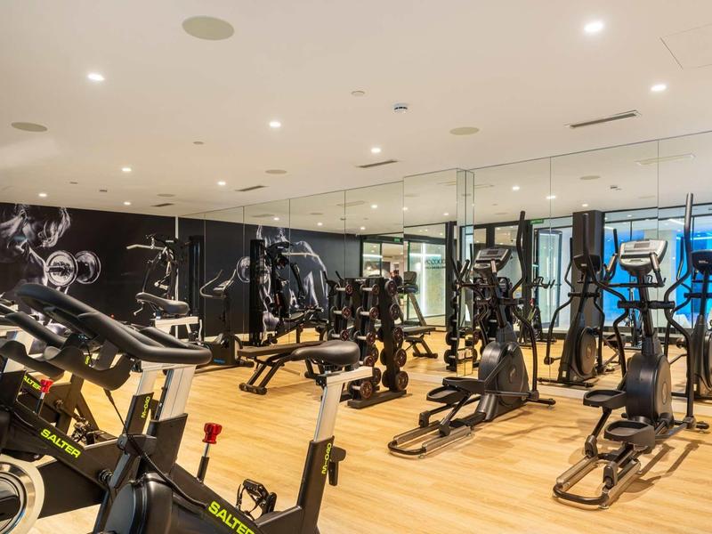 Palestra moderna con vari attrezzi da allenamento e pavimento in legno.