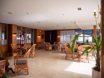 Salón luminoso y acogedor con muebles de mimbre y grandes ventanas con vistas al mar.