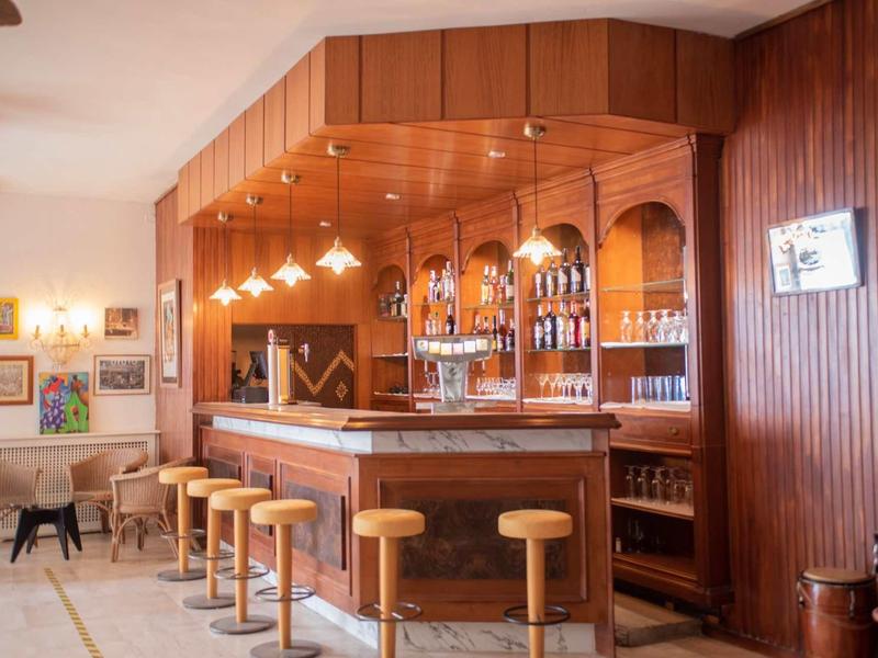 Pohodlný hotelový bar s dřevěným obložením, barovými stoličkami a teplým osvětlením.