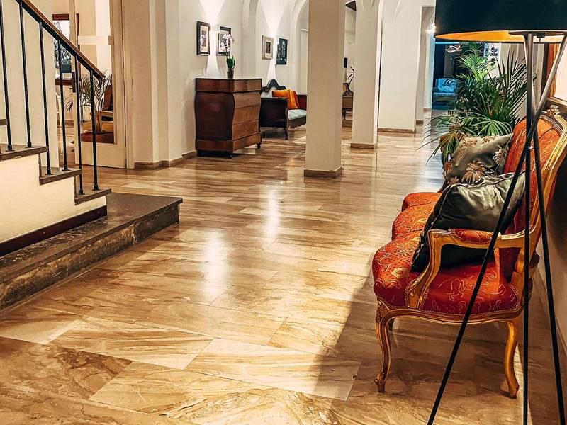 Světlá hotelová hala s mramorovou podlahou, oblouky a pohodlným posezením s kobercem.