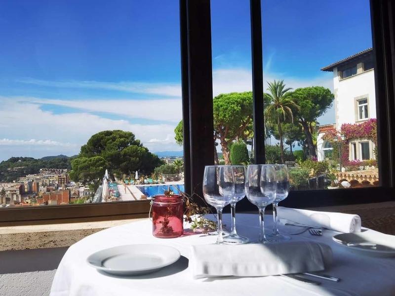 Elegantní stůl s bílým ubrusem s výhledem na středomořské budovy a moře.