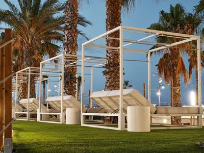 Luxurious hotel with pool, palm trees, and lounge chairs under sunny sky.