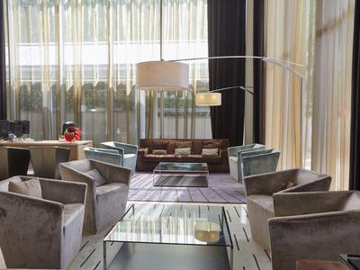 Modern hotel lobby with gray armchairs, a glass coffee table, and floor-to-ceiling windows.