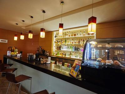 Area bar moderna dell'hotel con bancone in legno, sgabelli e scaffali illuminati sullo sfondo