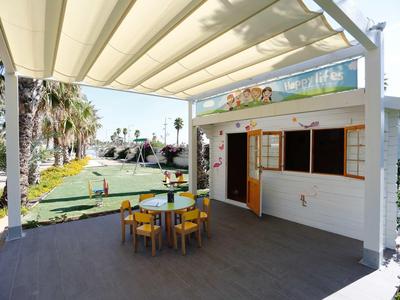 Shaded patio with table and chairs overlooking a mini golf course with palm trees.