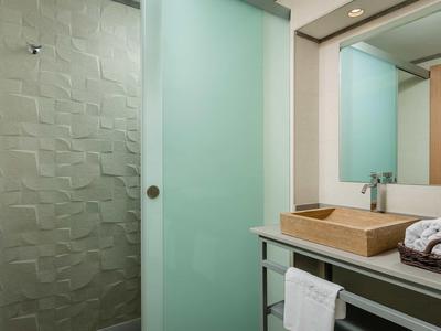 Modern bathroom with textured glass shower and wooden sink in hotel room.
