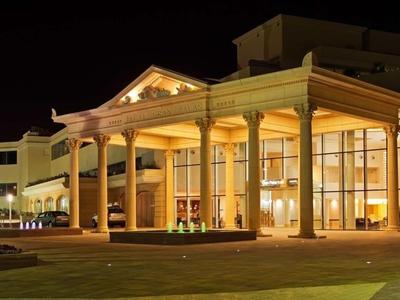 Grand hotel entrance with bright lighting and columns at night.