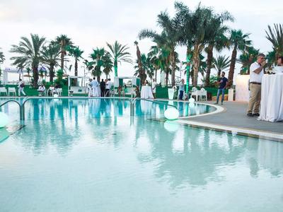 Luxury outdoor pool at a tropical resort with palm trees and white decorations.