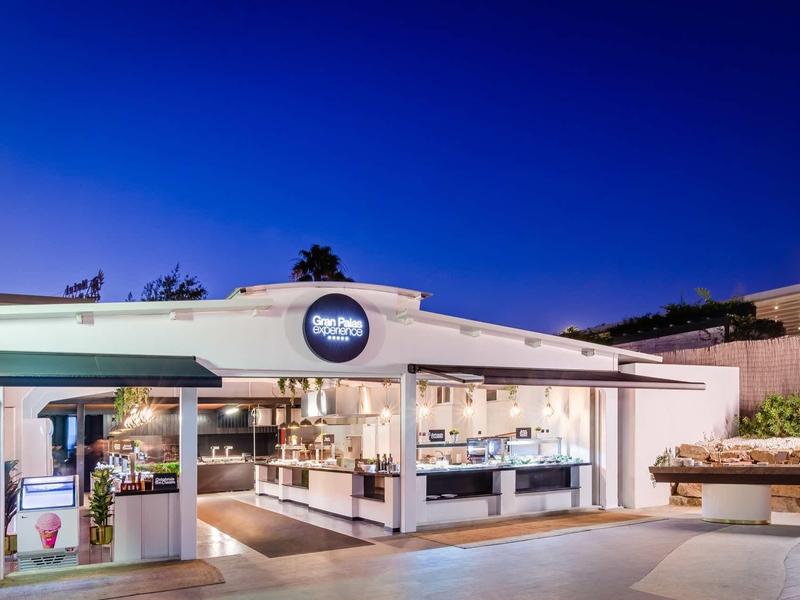Modern hotel lobby with bright lighting and blue evening sky backdrop.