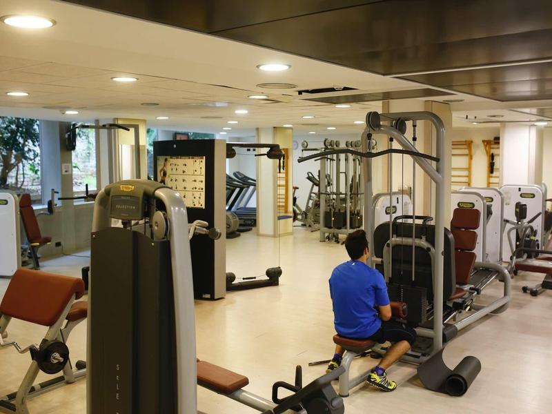 Modern gym with various exercise machines and a person working out in a spacious room.
