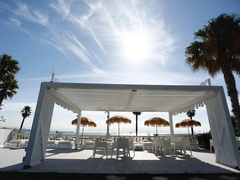 Outdoor patio with shaded seating and umbrellas under a bright, sunny sky.