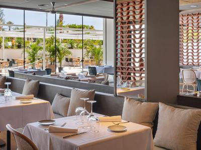 Hell eingerichtetes Restaurant mit gedeckten Tischen und Blick auf die Terrasse