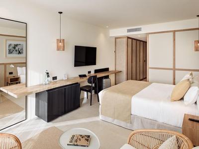 Modern eingerichtetes Hotelzimmer mit Doppelbett, Sitzbereich, TV und Schreibtisch.