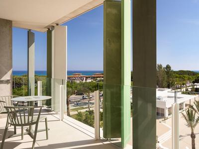 Balcone con tavolo, sedie e vista sul mare e sugli edifici vicini.