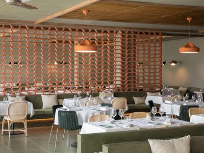 Ristorante moderno con tavoli ordinati, sedie eleganti e pannelli decorativi alle pareti.