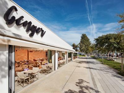 Area esterna del ristorante Ginger con tavoli e sedie sotto una tenda bianca.