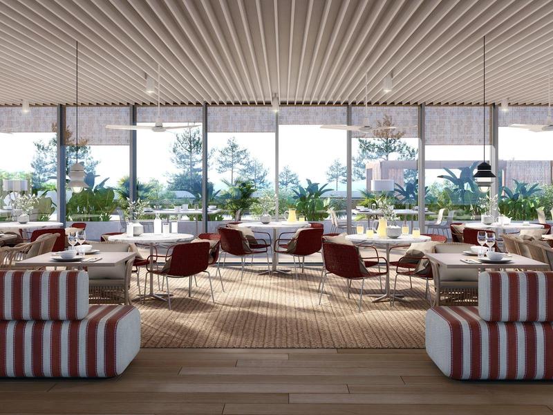 Ampia sala da pranzo dell'hotel con divani a righe, sedie rosse e grandi finestre con vista sul verde.