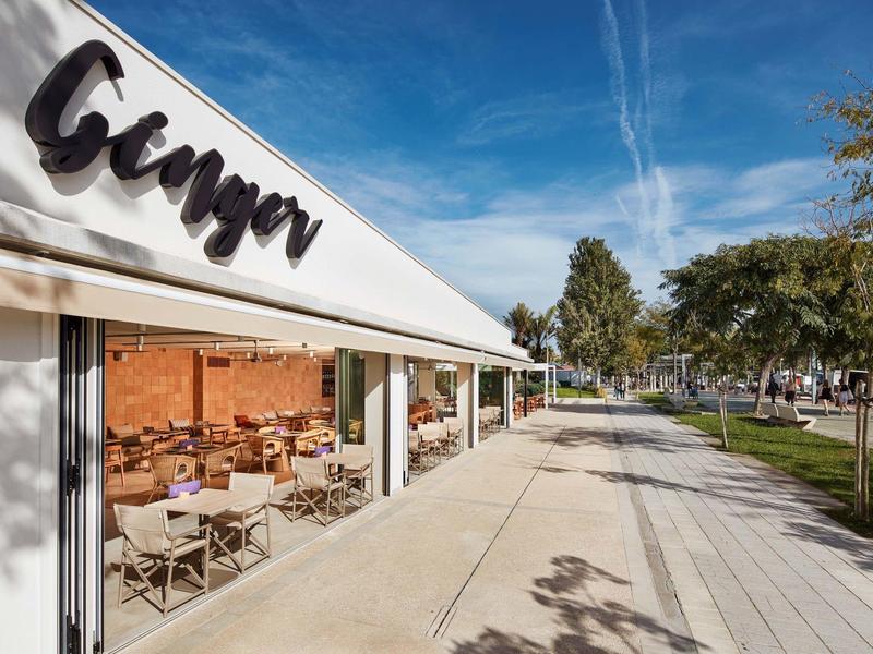 Area esterna del ristorante Ginger con tavoli e sedie sotto una tenda bianca.