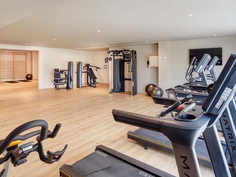 Palestra spaziosa con tapis roulant, pesi e macchine per esercizi in una stanza luminosa.